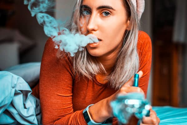 mujer fumando con una Shisha y echando humo por la boca