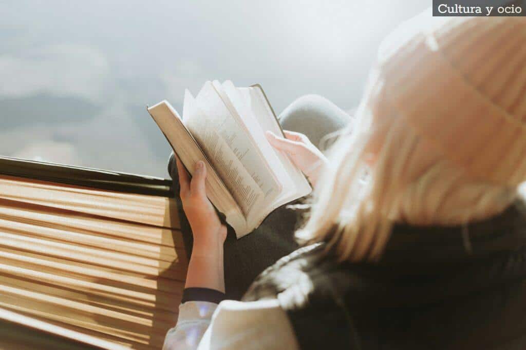 woman sitting on brown ledge while holding book